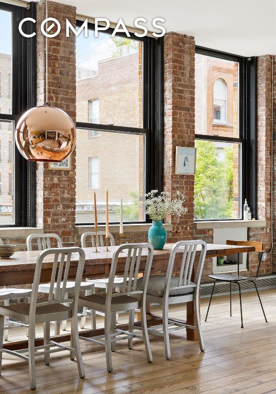 dining area featuring hardwood / wood-style flooring and brick wall