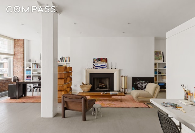 living room featuring wood finished floors, a fireplace with raised hearth, and brick wall