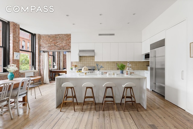 kitchen featuring extractor fan, backsplash, modern cabinets, and appliances with stainless steel finishes