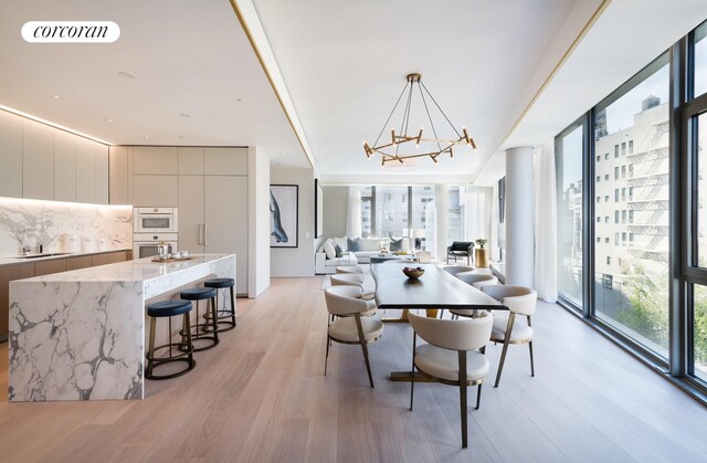 dining space featuring visible vents, light wood-style floors, a notable chandelier, and expansive windows