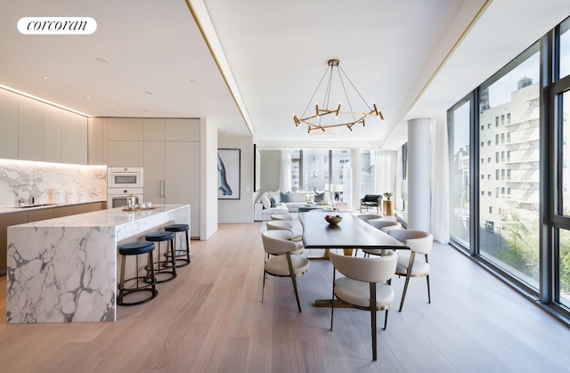 dining area featuring a chandelier, visible vents, floor to ceiling windows, and light wood-style floors