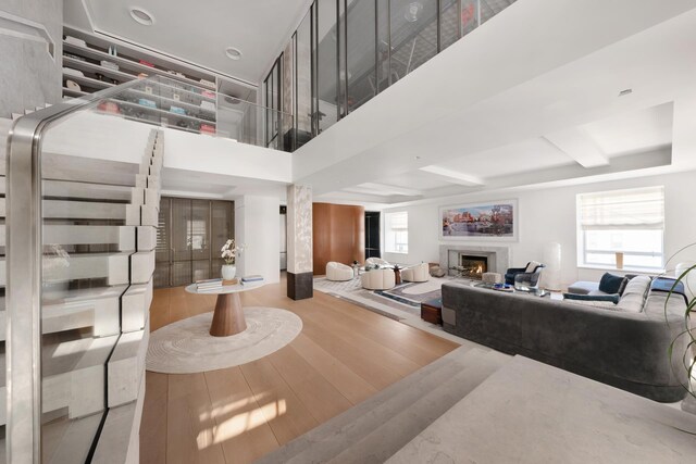 living room featuring a high end fireplace, wood finished floors, and a towering ceiling