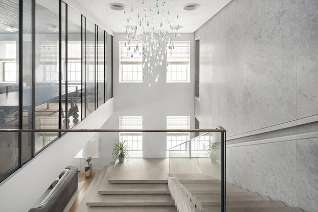 staircase with a chandelier and a towering ceiling