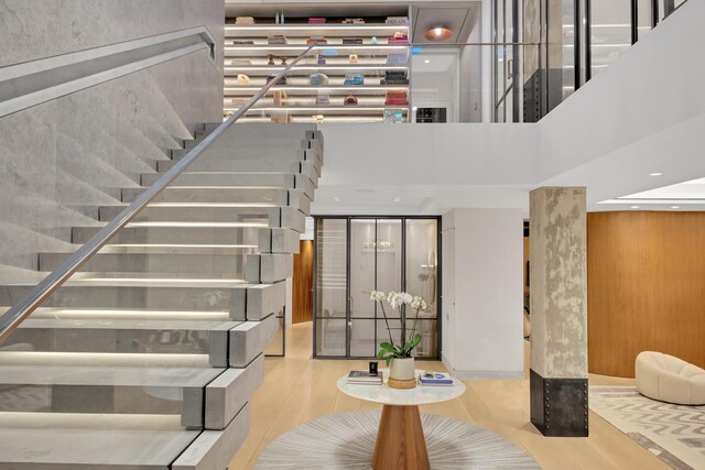 staircase with a high ceiling, wood finished floors, and recessed lighting