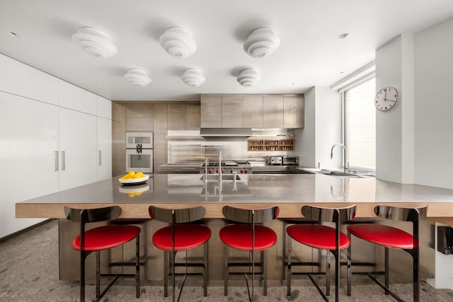 kitchen with modern cabinets, a breakfast bar, backsplash, a peninsula, and white oven