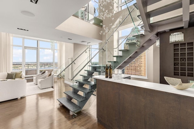 staircase featuring expansive windows, hardwood / wood-style floors, and a notable chandelier