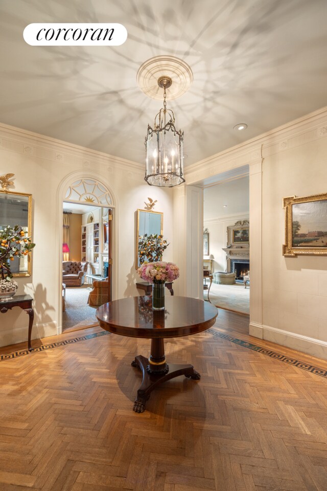 corridor with an inviting chandelier, crown molding, and parquet flooring