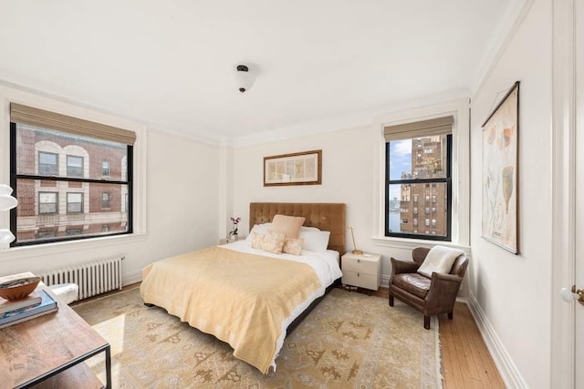 bedroom with light wood-type flooring, radiator heating unit, and ornamental molding