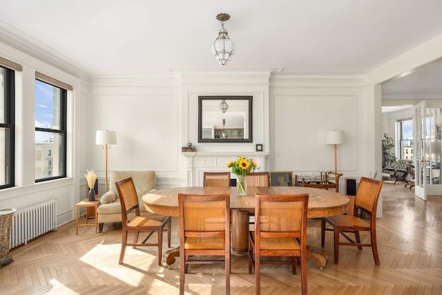 dining area featuring light parquet flooring, radiator heating unit, and ornamental molding