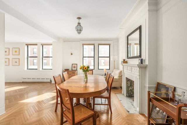 dining space featuring a baseboard heating unit, a wealth of natural light, light parquet floors, and ornamental molding