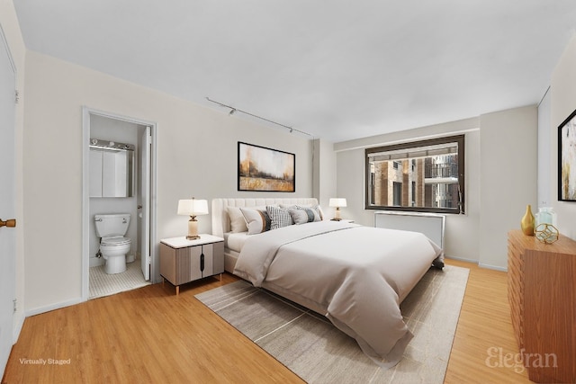 bedroom with light hardwood / wood-style flooring and ensuite bath