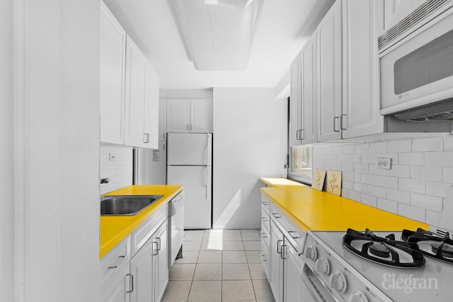 kitchen featuring white cabinetry, sink, decorative backsplash, light tile patterned floors, and white appliances