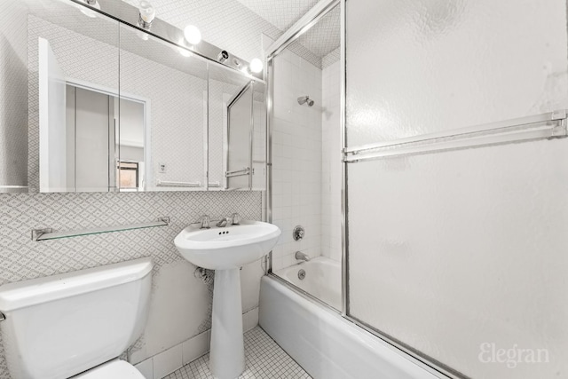 bathroom featuring tile patterned flooring, decorative backsplash, bath / shower combo with glass door, and toilet