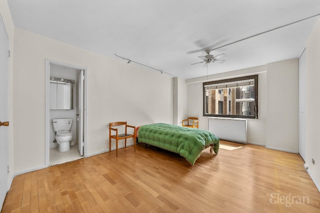 bedroom with ceiling fan, ensuite bathroom, radiator, and light hardwood / wood-style floors