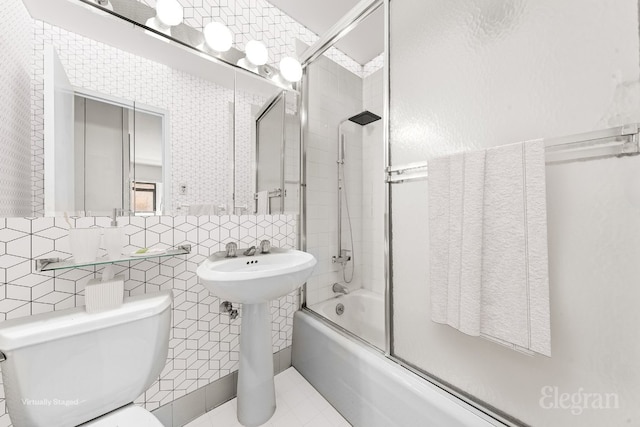 bathroom featuring tile patterned flooring, decorative backsplash, bath / shower combo with glass door, toilet, and tile walls