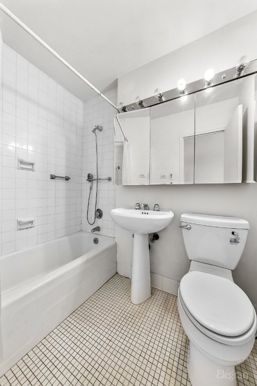 full bathroom featuring toilet, tiled shower / bath combo, tile patterned flooring, and sink