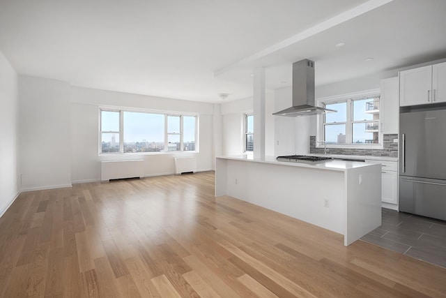 60 E 8th St Unit 27-N, New York City, NY 10003 - kitchen featuring appliances with stainless steel finishes, island range hood, light wood-type flooring, and open floor plan