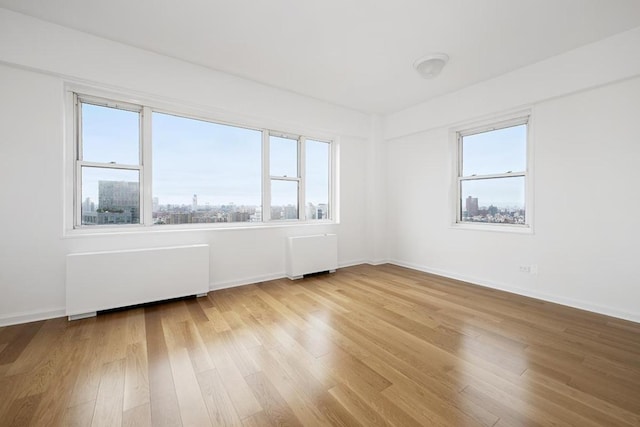 empty room featuring radiator heating unit and light hardwood / wood-style floors