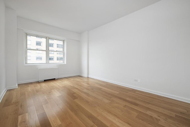 empty room featuring radiator and light hardwood / wood-style flooring