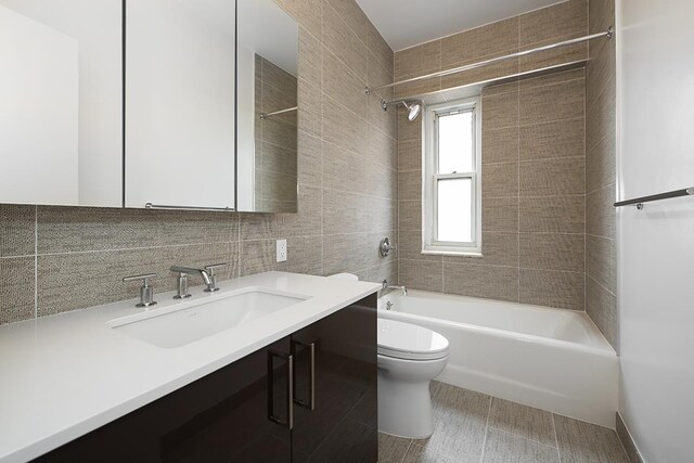 full bathroom with tiled shower / bath, tasteful backsplash, tile walls, vanity, and toilet