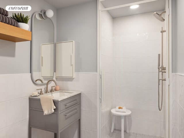 bathroom featuring walk in shower, vanity, and tile walls