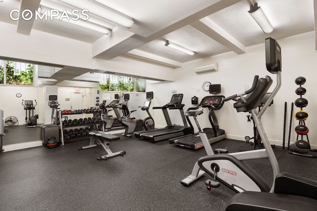 workout area with a healthy amount of sunlight, a wall unit AC, and baseboards