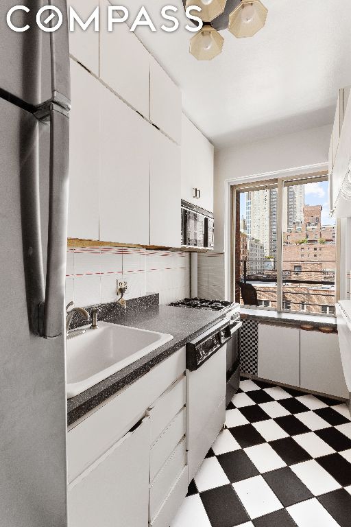 kitchen featuring white cabinetry, sink, backsplash, and white dishwasher