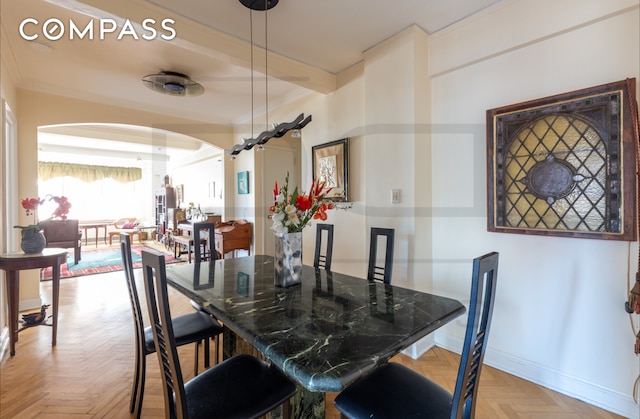 dining space with baseboards, arched walkways, beam ceiling, and ornamental molding