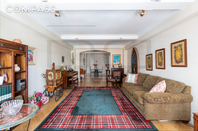 living area with arched walkways and a raised ceiling