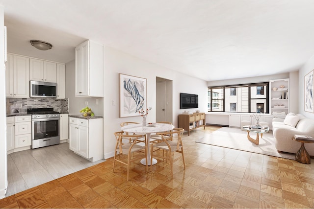 85 Livingston St Unit 15L, New York City, NY 11201 - kitchen with stainless steel appliances, open floor plan, white cabinetry, dark countertops, and backsplash