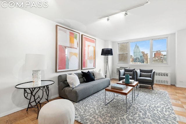 living room featuring radiator, rail lighting, and parquet flooring