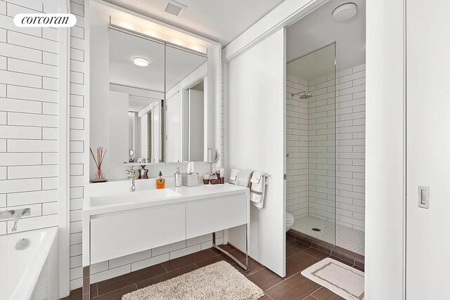 bathroom featuring a tile shower, vanity, tile patterned flooring, and toilet