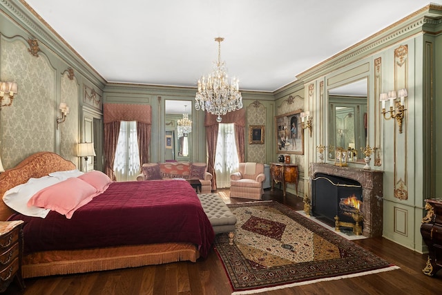 bedroom featuring wallpapered walls, dark wood-style floors, ornamental molding, a fireplace, and a chandelier