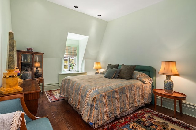 bedroom with a baseboard heating unit and dark wood finished floors