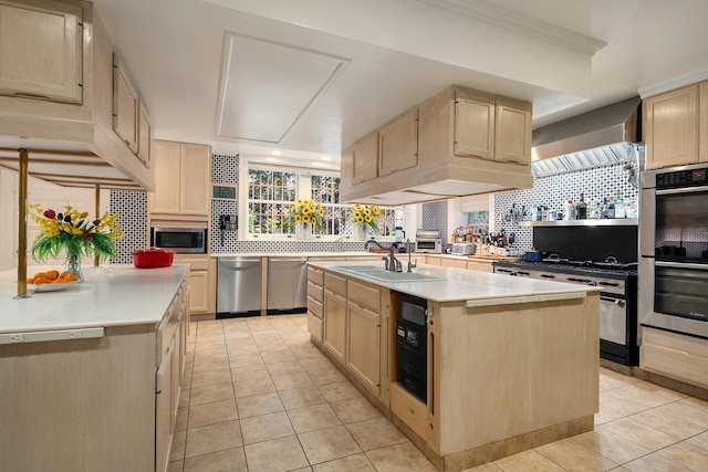 kitchen featuring an island with sink, light brown cabinets, appliances with stainless steel finishes, and light countertops