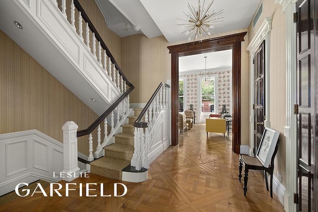 stairway featuring an inviting chandelier and parquet floors