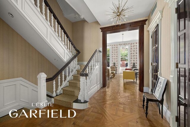 159 E 71st St, New York City, NY 10021 - stairs with a notable chandelier, baseboards, wallpapered walls, a wainscoted wall, and visible vents