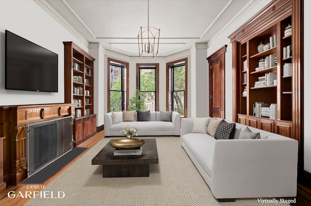 living area with an inviting chandelier, a fireplace, light wood-style flooring, ornamental molding, and built in shelves