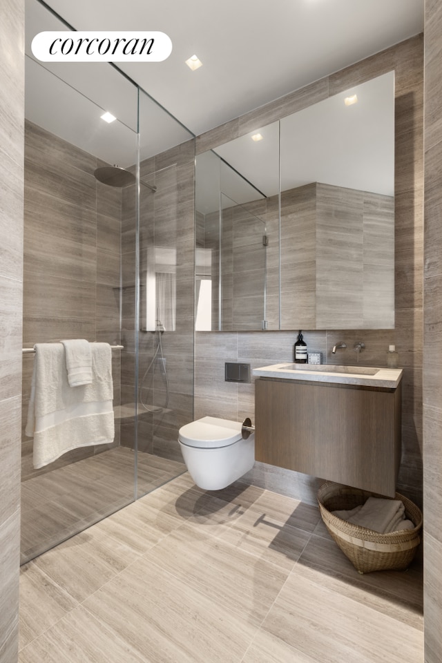 full bathroom with a shower stall, tile patterned flooring, toilet, vanity, and tile walls