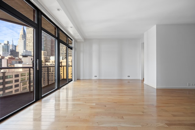 100 United Nations Plz Unit 20E, New York City, NY 10017 - spare room with wood finished floors, baseboards, a view of skyline, and expansive windows