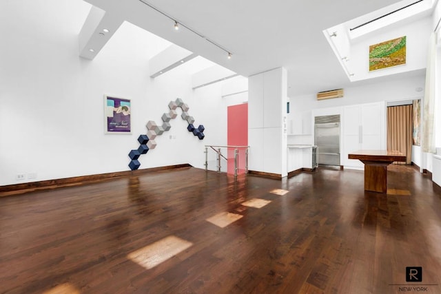 spare room with rail lighting, dark wood finished floors, and baseboards