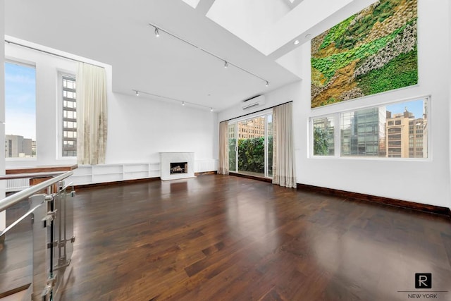 unfurnished living room with a view of city, a fireplace, dark wood finished floors, and a wall mounted air conditioner