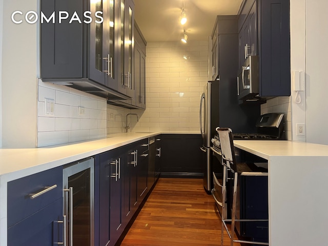 60 E 8th St Unit 23D, New York City, NY 10003 - kitchen with wine cooler, stainless steel microwave, dark wood finished floors, tasteful backsplash, and light countertops