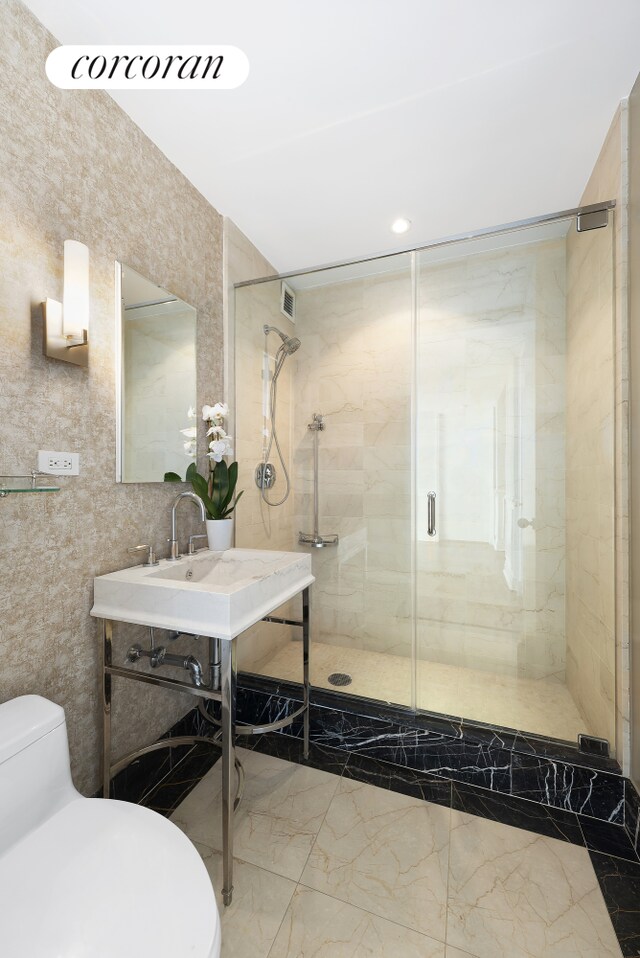 25 Columbus Cir Unit 55F, New York City, NY 10019 - bathroom featuring marble finish flooring, toilet, a shower stall, and tile walls