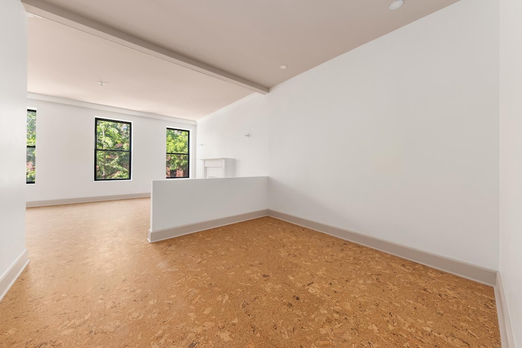 spare room with vaulted ceiling with beams and baseboards