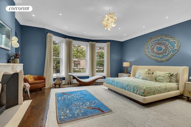 bedroom featuring crown molding, hardwood / wood-style flooring, a fireplace, and an inviting chandelier