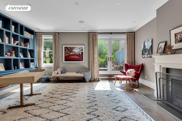 sitting room with visible vents, crown molding, baseboards, a fireplace with flush hearth, and wood finished floors