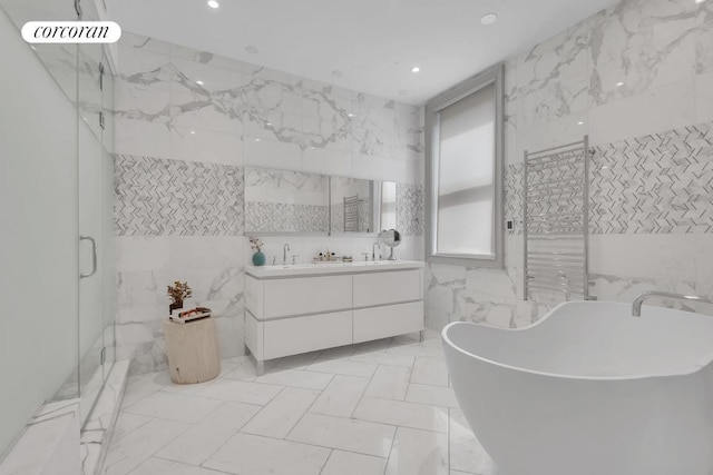 bathroom featuring vanity, independent shower and bath, and tile walls