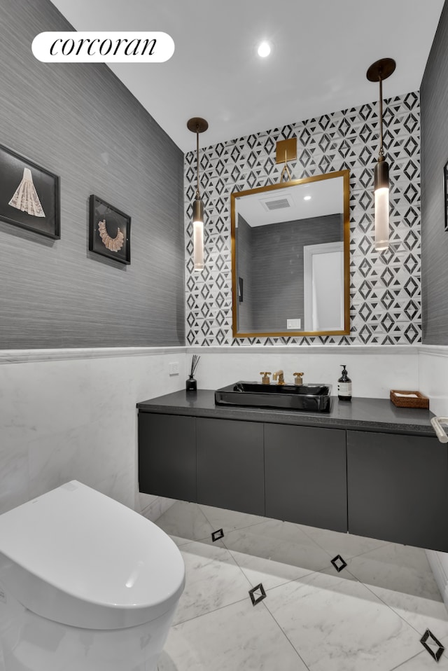 bathroom featuring marble finish floor, tile walls, and vanity