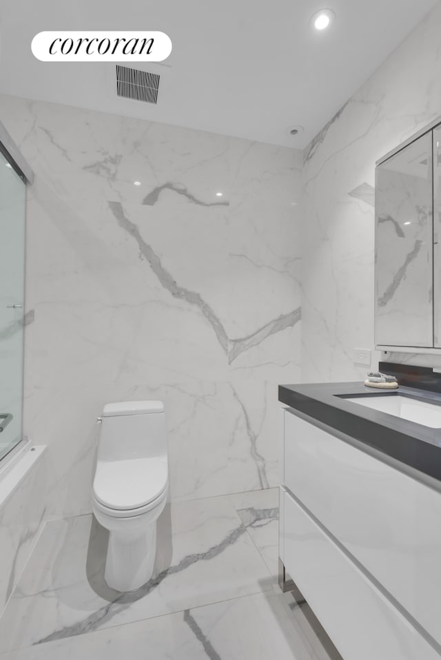 full bathroom featuring toilet, vanity, recessed lighting, marble finish floor, and stone wall